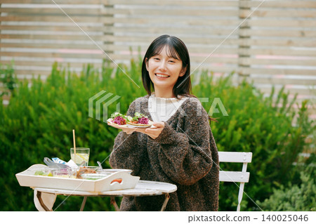 一位女士在花園裡吃墨西哥捲餅 140025046