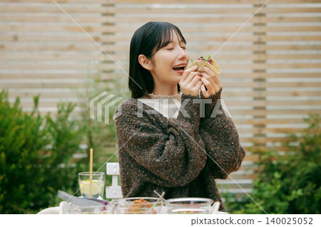 一位女士在花園裡吃墨西哥捲餅 140025052
