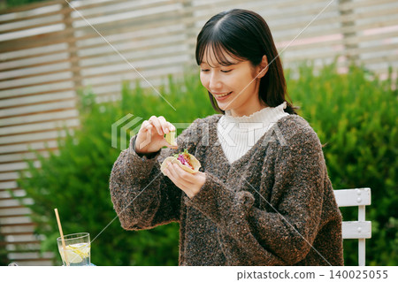 一位女士在花園裡吃墨西哥捲餅 一位女士在花園裡吃墨西哥捲餅 140025055