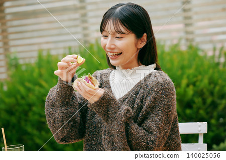 一位女士在花園裡吃墨西哥捲餅 一位女士在花園裡吃墨西哥捲餅 140025056