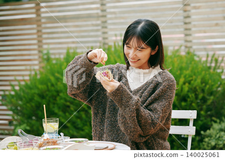 一位女士在花園裡吃墨西哥捲餅 140025061
