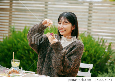 一位女士在花園裡吃墨西哥捲餅 140025064