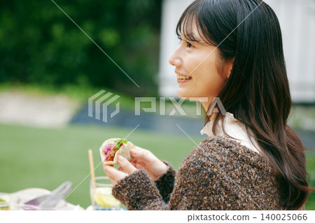 一位女士在花園裡吃墨西哥捲餅 140025066