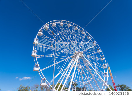 Ferris wheel under blue sky, capturing fun and adventure on a sunny day. Ferris wheel at the amusement park adjacent to the hotel Ferris wheel under blue sky, capturing fun and adventure on a sunny day. Ferris wheel at the amusement park adjacent to the hotel 140025136