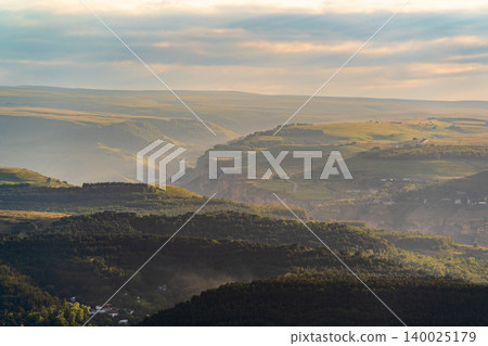Layers of green mountains and hills in the haze during sunset. Panoramic View of Green hills and Meadow. 140025179