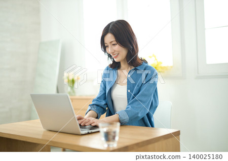 Middle-aged woman working on a laptop 140025180