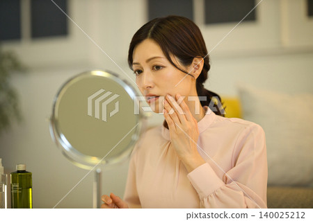 中年女性在夜間護膚過程中會擔心皮膚問題。 中年女性在夜間護膚過程中會擔心皮膚問題。 140025212