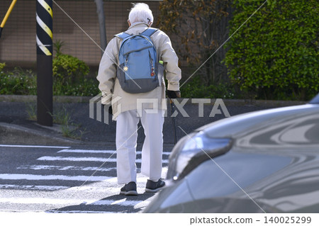 An elderly man with a cane (wearing a mask) crosses a pedestrian crossing in Yokohama, Japan. A dark shadow sways across the crosswalk... What is life...? An elderly man with a cane (wearing a mask) crosses a pedestrian crossing in Yokohama, Japan. A dark shadow sways across the crosswalk... What is life...? 140025299