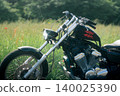A custom motorcycle standing in a grassland, amidst a summer landscape. 140025390