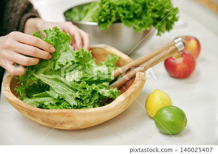 The hands that arrange fresh lettuce in a bowl The hands that arrange fresh lettuce in a bowl 140025407