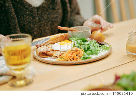 一位女士正在吃一份早餐,她的雙手在吃早餐時。 一位女士正在吃一份早餐,她的雙手在吃早餐時。 140025410