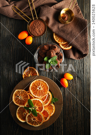 Sliced oranges, chocolate treats, and mint on a wooden table Sliced oranges, chocolate treats, and mint on a wooden table 140025628