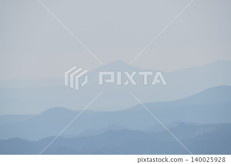 A distant view of the snow-capped mountains of Hokkaido's Daisetsuzan Mountains, a thick spring haze, and a minimalist mountain landscape with a blue gradient (May). A distant view of the snow-capped mountains of Hokkaido's Daisetsuzan Mountains, a thick spring haze, and a minimalist mountain landscape with a blue gradient (May). 140025928
