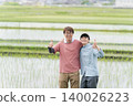 Two farmers strike a thumbs-up in a rice field. Two farmers strike a thumbs-up in a rice field. 140026223