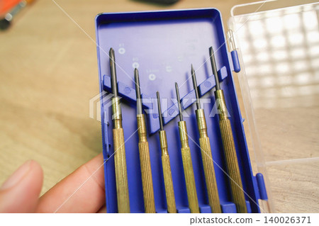 A hand holding brass precision screwdrivers set A hand holding brass precision screwdrivers set 140026371
