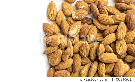 Raw almonds scattered on a white background in a clean minimal composition. Natural healthy snack ingredient shown in a top view with visible nut texture 140026501