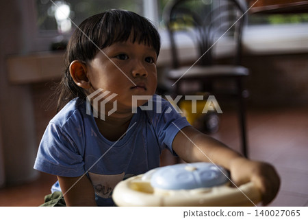 Little Boy Driving A Plastic Ride On Car In Playroom. Cute asian toddler boy playing with a colorful toy car at home, perfect for childhood, early development and family lifestyle themes. Little Boy Driving A Plastic Ride On Car In Playroom. Cute asian toddler boy playing with a colorful toy car at home, perfect for childhood, early development and family lifestyle themes. 140027065