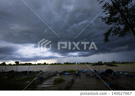 Storm Clouds Gathering Over Chao Phraya River In Chai Nat. Dramatic dark clouds forming over the river landscape in Thailand, perfect for weather, nature and climate change themes. 140027067