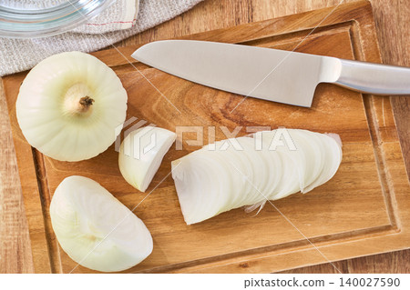 New onions being thinly sliced on a cutting board during preparation. New onions being thinly sliced on a cutting board during preparation. 140027590