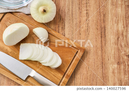 New onions being thinly sliced on a cutting board during preparation. New onions being thinly sliced on a cutting board during preparation. 140027596