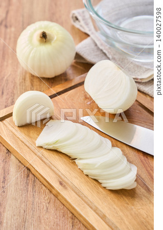New onions being thinly sliced on a cutting board during preparation. New onions being thinly sliced on a cutting board during preparation. 140027598