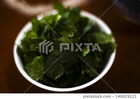 Fresh Plucked Coriander Leaves In A Small Bowl, organic green cilantro, background for fresh food marketing campaign, brand awareness, culinary ingredient and agricultural product. 140029221