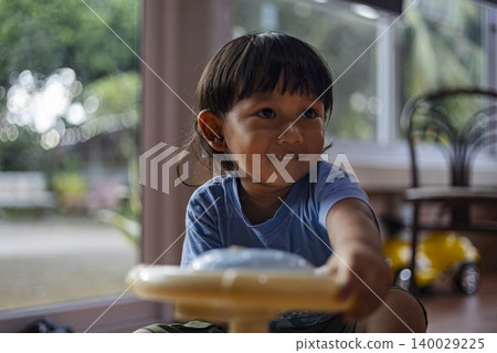 Little Boy Driving A Plastic Ride On Car In Playroom. Cute asian toddler boy playing with a colorful toy car at home, perfect for childhood, early development and family lifestyle themes. Little Boy Driving A Plastic Ride On Car In Playroom. Cute asian toddler boy playing with a colorful toy car at home, perfect for childhood, early development and family lifestyle themes. 140029225