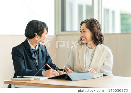 Elementary, middle, and high school students in school uniforms studying using tablets, along with their mothers, teachers, and instructors. 140030373