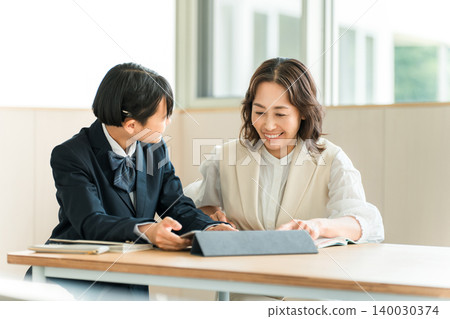 Elementary, middle, and high school students in school uniforms studying using tablets, along with their mothers, teachers, and instructors. 140030374