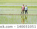 Two farmers standing on the embankment of a rice paddy. Two farmers standing on the embankment of a rice paddy. 140031051