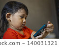 Toddler Using Smartphone To Call His Mother In The Room. Cute asian little boy pretending to make a phone call to his mom, ideal for family lifestyle, technology and childhood development themes. 140031321