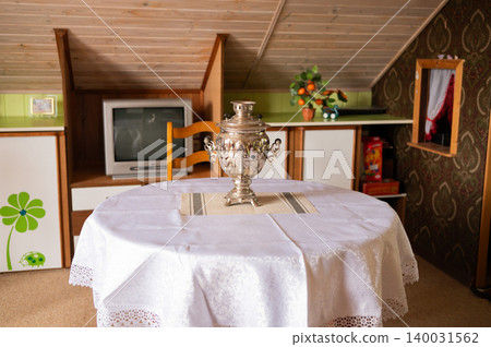 Antique samovar resting on lace covered table in attic room Antique samovar resting on lace covered table in attic room 140031562