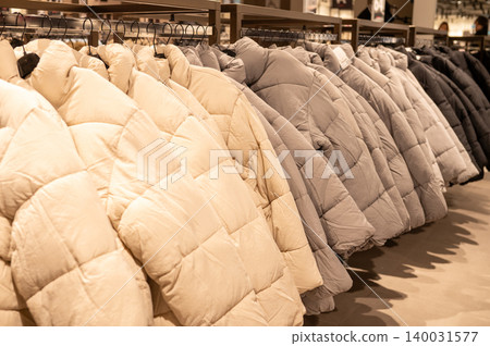 Row of beige and gray puffer jackets in clothing store display Row of beige and gray puffer jackets in clothing store display 140031577
