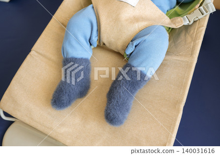 Infant wearing fuzzy socks seated in fabric baby carrier Infant wearing fuzzy socks seated in fabric baby carrier 140031616