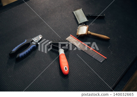 Grooming tools for dogs arranged on a textured black surface, including scissors, combs, and brushes, ideal for pet care and grooming professionals Grooming tools for dogs arranged on a textured black surface, including scissors, combs, and brushes, ideal for pet care and grooming professionals 140032665