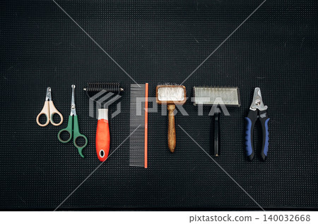 Grooming tools for dogs arranged on a black surface, including scissors, combs, and brushes, showcasing a variety of pet grooming equipment Grooming tools for dogs arranged on a black surface, including scissors, combs, and brushes, showcasing a variety of pet grooming equipment 140032668