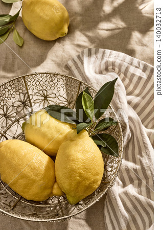 Fresh Italian Lemons in decorative bowl on a Linen Tablecloth in Warm Tones. Top View Fresh Italian Lemons in decorative bowl on a Linen Tablecloth in Warm Tones. Top View 140032718