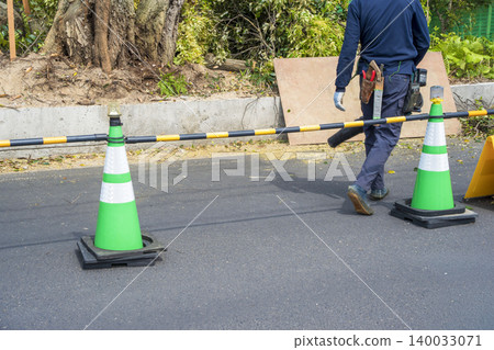 A person using a blower to clean up trash from the road. 140033071