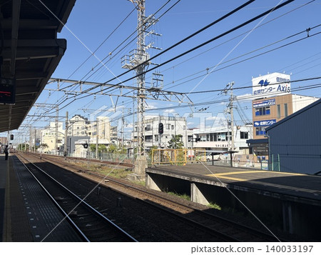A view of the Nankai Electric Railway station platform and double tracks under a clear blue sky. A view of the Nankai Electric Railway station platform and double tracks under a clear blue sky. 140033197