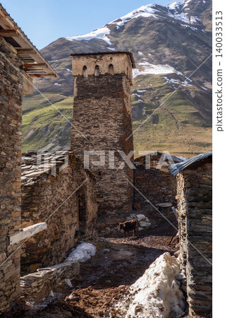Stone tower stands tall beside ancient buildings. Ushguli in Georgia. 140033513