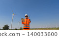 Female wind farm engineer reviewing data on digital tablet while using walkie talkie at wind energy site 140033600