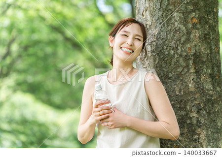 A relaxed woman drinking bottled water, mineral water, and hot water. 140033667