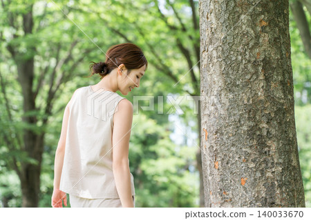 A young Asian woman under a tree in a park (Botanical, Organic, Nature, Natural, Forest bathing) A young Asian woman under a tree in a park (Botanical, Organic, Nature, Natural, Forest bathing) 140033670