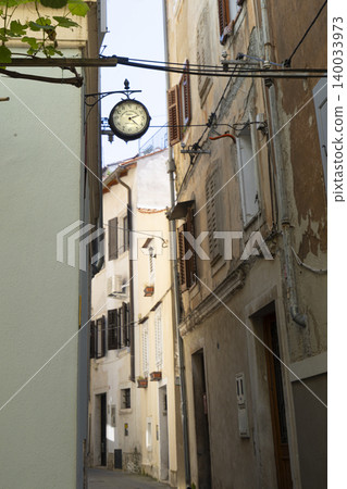 A vintage clock hangs above a narrow street in Piran, Slovenia A vintage clock hangs above a narrow street in Piran, Slovenia 140033973