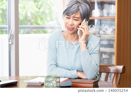 Senior woman making a phone call at home Senior woman making a phone call at home 140035254