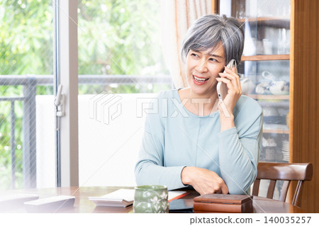 Senior woman making a phone call at home Senior woman making a phone call at home 140035257