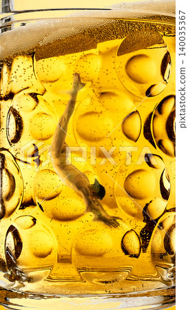 Female dancer upside down inside golden beer glass with bubble pattern Female dancer upside down inside golden beer glass with bubble pattern 140035367