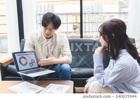 一男一女正在認真地討論一份文件中的圓餅圖。 140035944