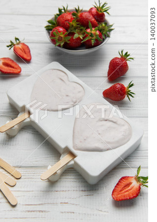 Preparing strawberry yogurt popsicles in heart shaped molds Preparing strawberry yogurt popsicles in heart shaped molds 140037093
