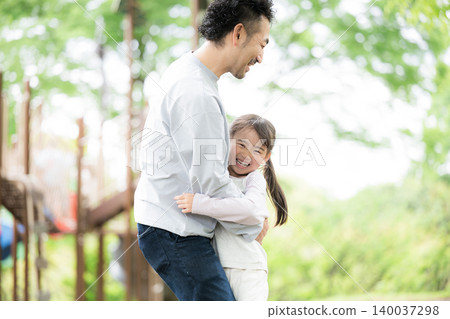A heartwarming image of a family interacting and raising children, with a father and daughter playing together in a park surrounded by fresh greenery. A heartwarming image of a family interacting and raising children, with a father and daughter playing together in a park surrounded by fresh greenery. 140037298